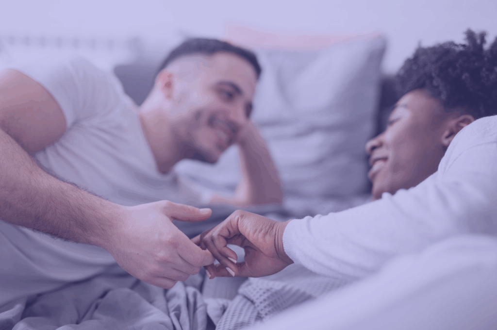 mixed couple in bed smiling and holding hands